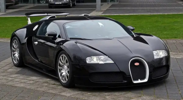 Czarny Bugatti Veyron, symbol luksusu i mocy, prezentuje się na tle innych drogich marek samochodów.