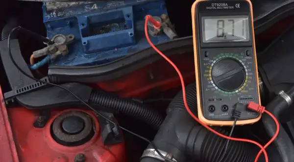 Sprawdzanie akumulatora multimetrem, by dowiedzieć się, jak odpalić auto z rozładowanym akumulatorem. Wynik 8.71V wskazuje na problem.