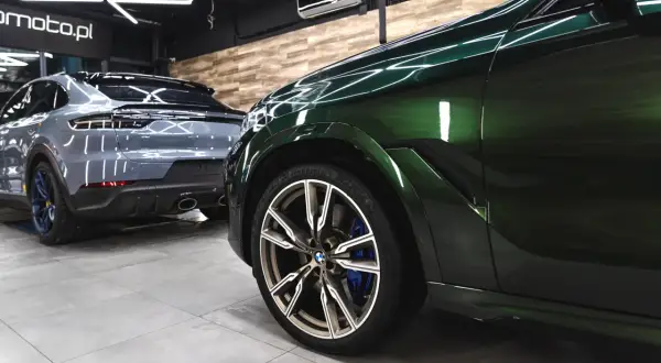 Zielony BMW i szary Porsche w garażu. To praca detailera, który dba o każdy detal.