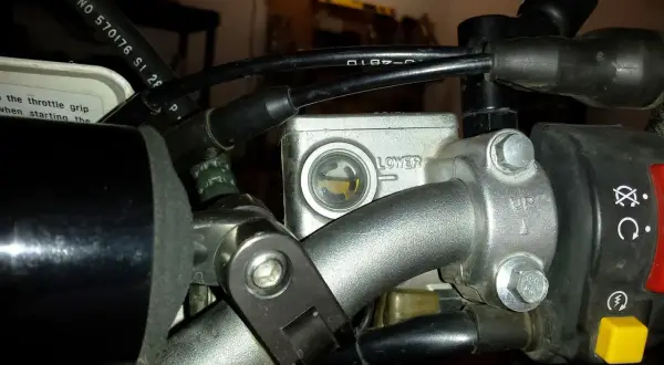 Zbiorniczek płynu hamulcowego motocykla z widocznym poziomem płynu.
