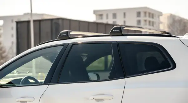Biały SUV z zamontowanymi relingami dachowymi Yakima. Różne rodzaje relingów dachowych pozwalają na przewożenie bagażu.