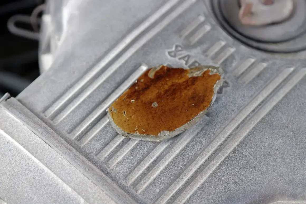 Fragment metalowej obudowy silnika z widocznym, lekko przytartym elementem o brązowym zabarwieniu.