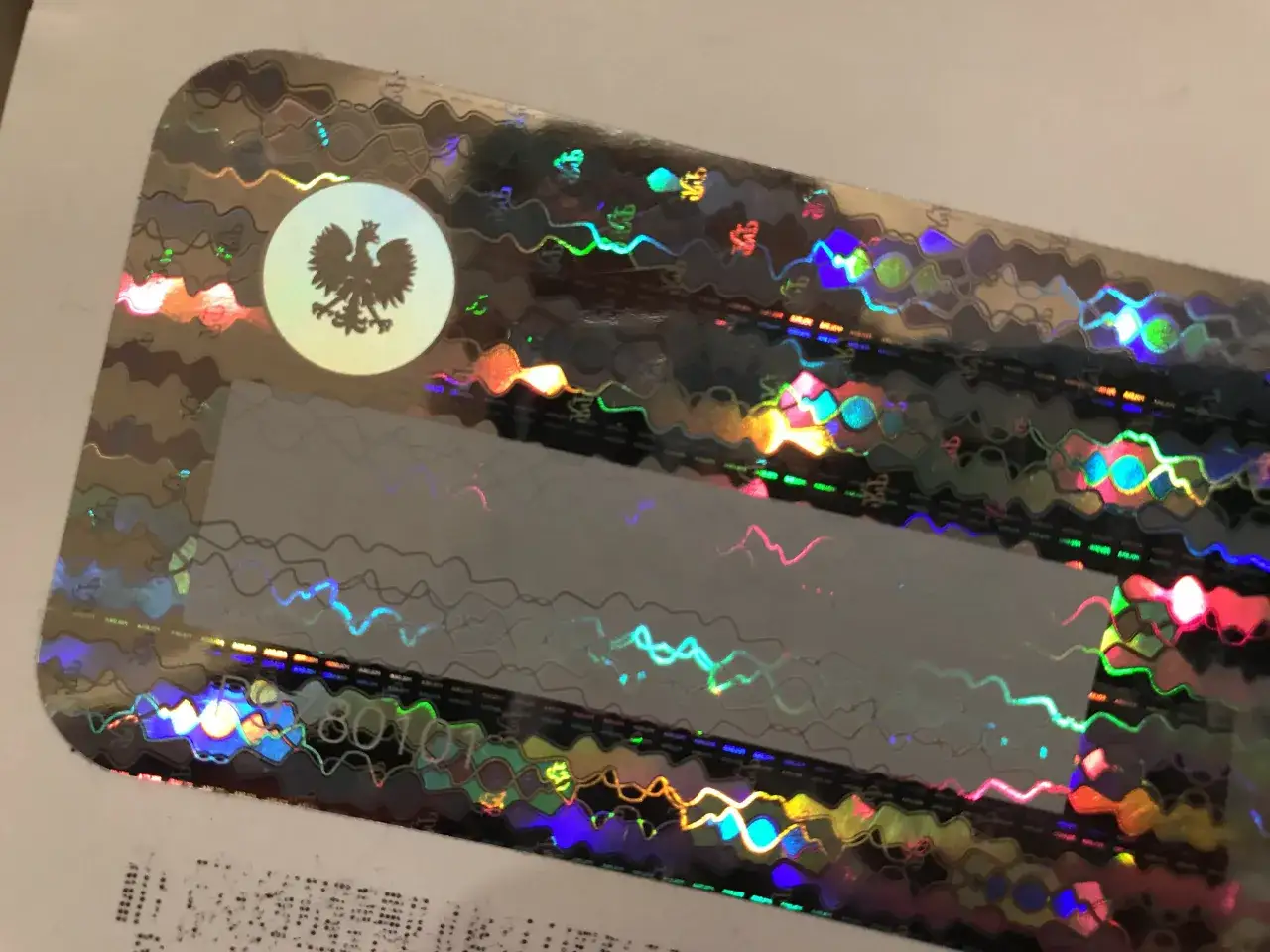 Holograficzna naklejka z orłem. Dowiedz się, jak usunąć naklejkę z szyby bez suszarki, by uniknąć uszkodzeń.
