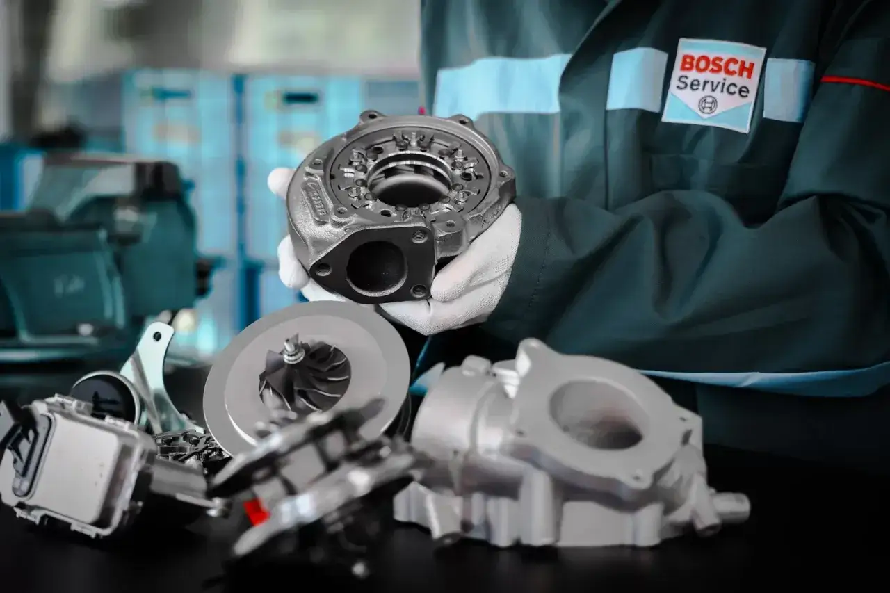 Mechanik w białych rękawiczkach prezentuje części turbosprężarki. Dowiedz się, jak sprawdzić turbinę w dieslu, by zapewnić jej sprawność.