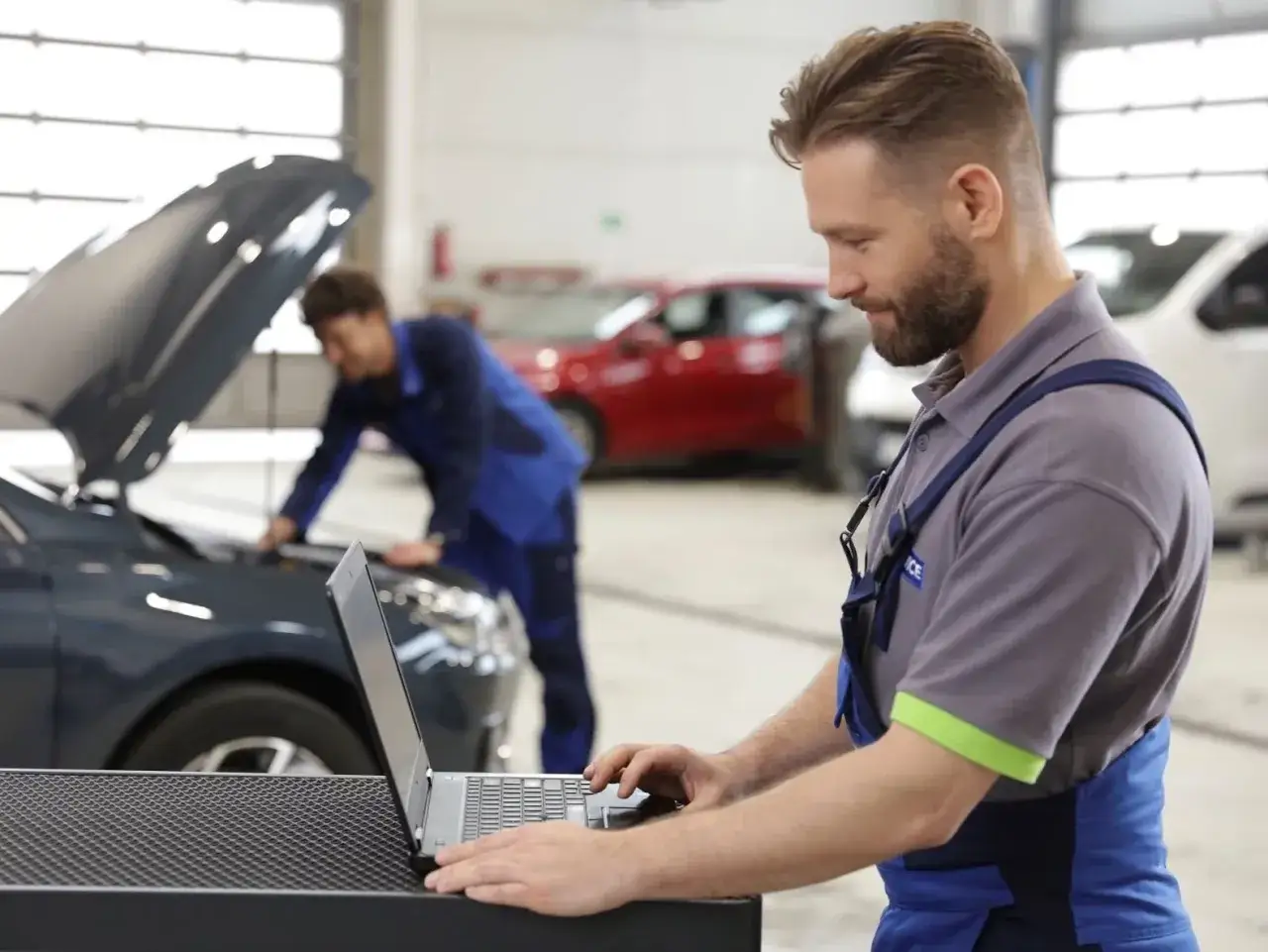 Mechanik wykonuje diagnostykę komputerową samochodu, analizując dane na laptopie.