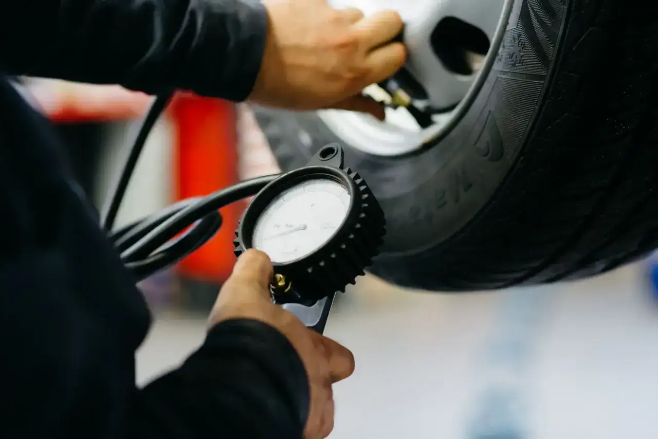 Mechanik sprawdza ciśnienie w oponie, przygotowując wymianę opon z czujnikami ciśnienia.