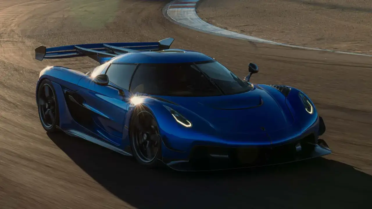 Niebieski Koenigsegg Jesko Attack pędzi po torze wyścigowym, jego aerodynamiczna sylwetka i potężne skrzydło budzą respekt.