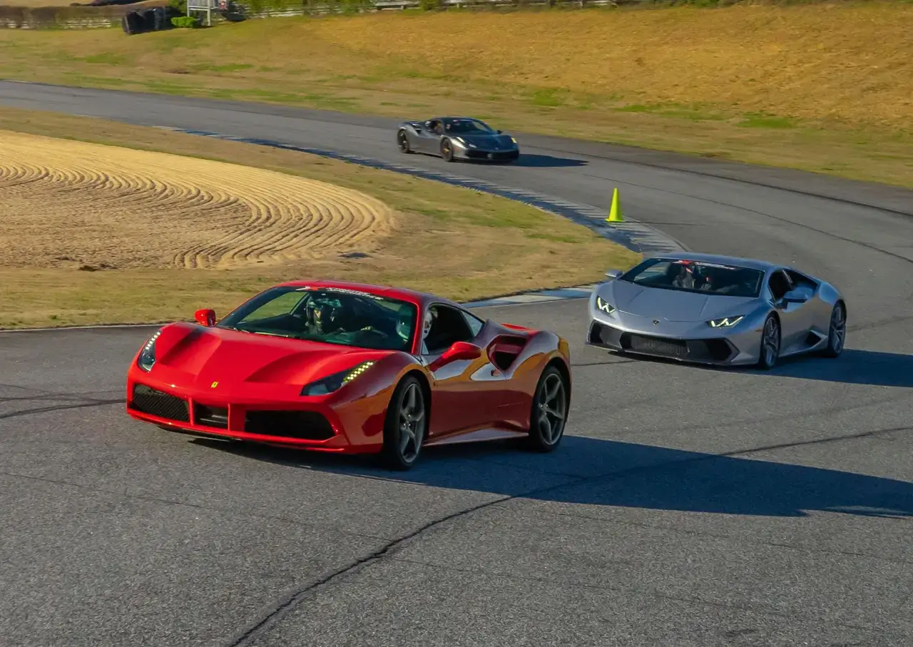 Czerwone Ferrari i srebrne Lamborghini ścigają się na torze wyścigowym.
