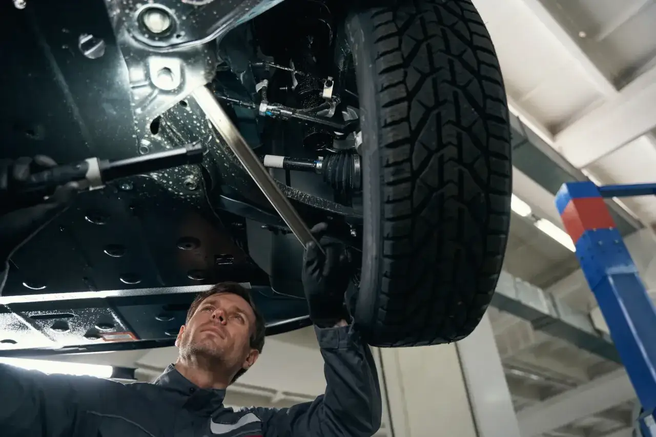 Mechanik sprawdza podwozie auta, szukając przyczyny rytmicznego stukania podczas jazdy.