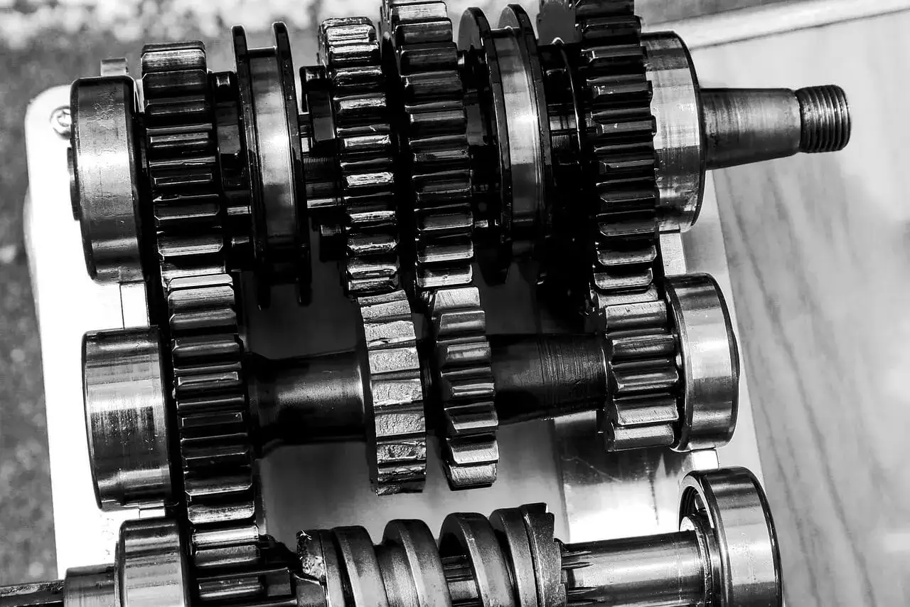 Metalowe tryby skrzyni biegów, które wyglądają na zużyte. Widać, że ciężko wchodzą biegi, co sugeruje potrzebę naprawy.