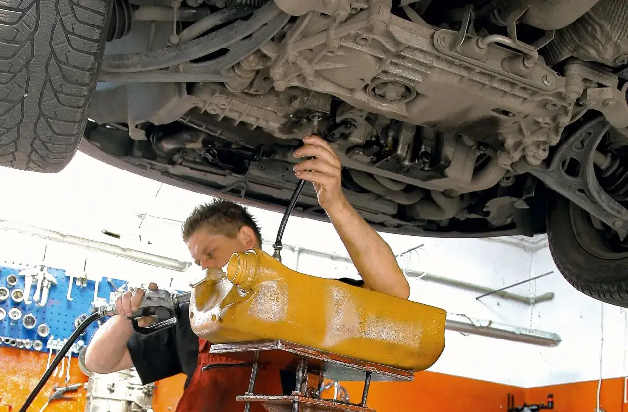 Mechanik podczas naprawy skrzyń DSG wymienia olej w skrzyni biegów.