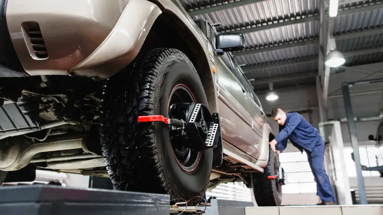 Mechanik sprawdza prawidłową zbieżność kół w samochodzie terenowym, używając specjalistycznego sprzętu.