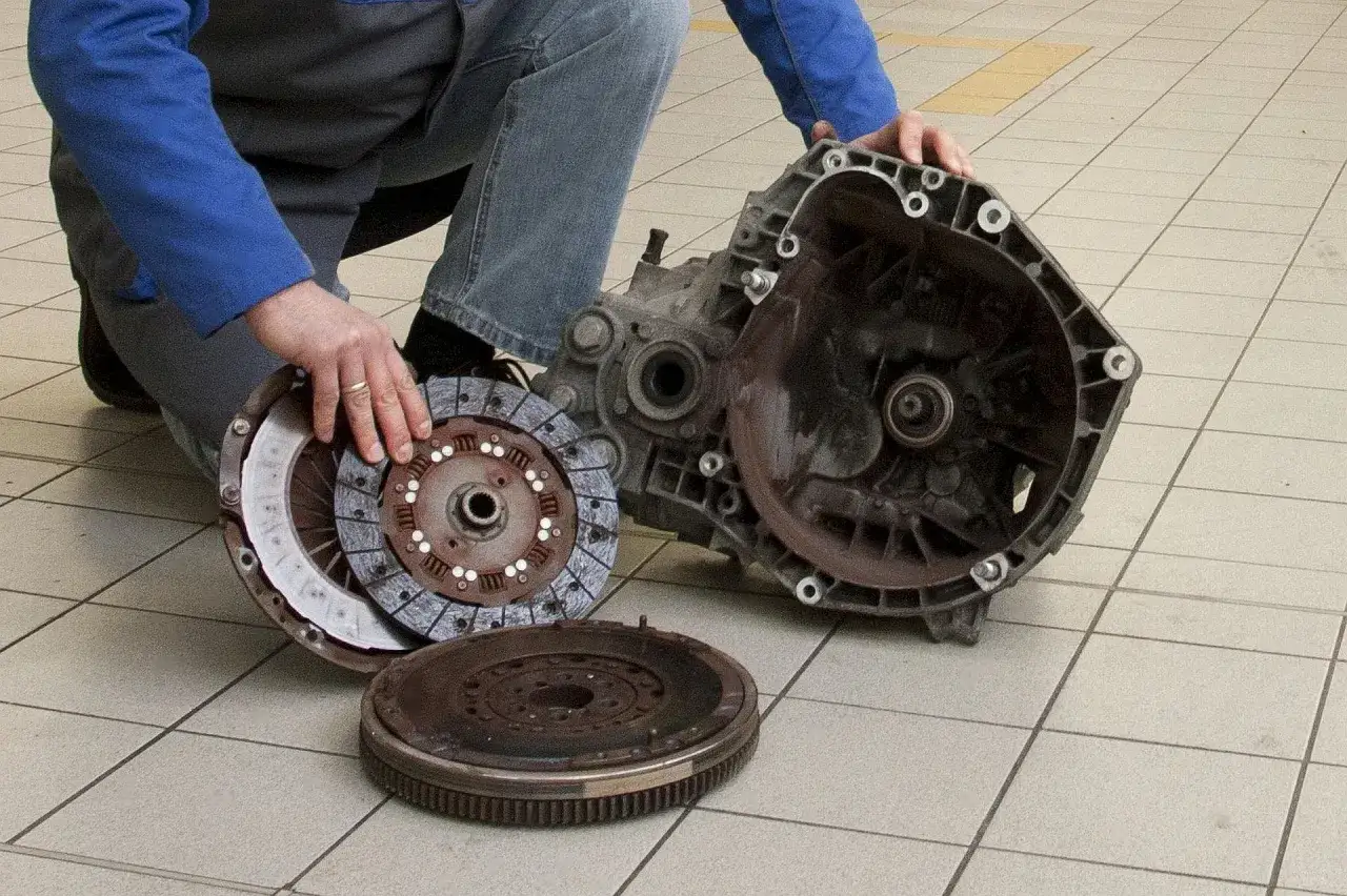 Mechanik pokazuje elementy sprzęgła: tarczę, docisk i koło zamachowe. Objawy zużycia łożyska oporowego mogą być różne.
