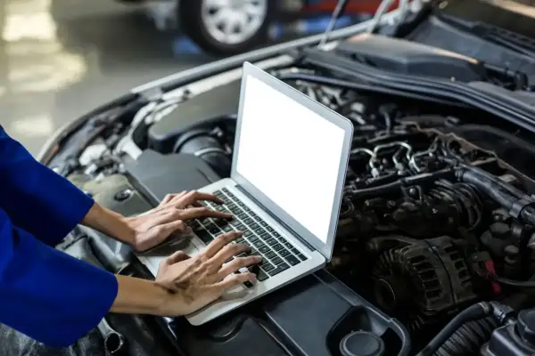 Mechanik diagnozuje szarpanie na niskich obrotach benzyna, analizując dane z komputera pod maską samochodu.