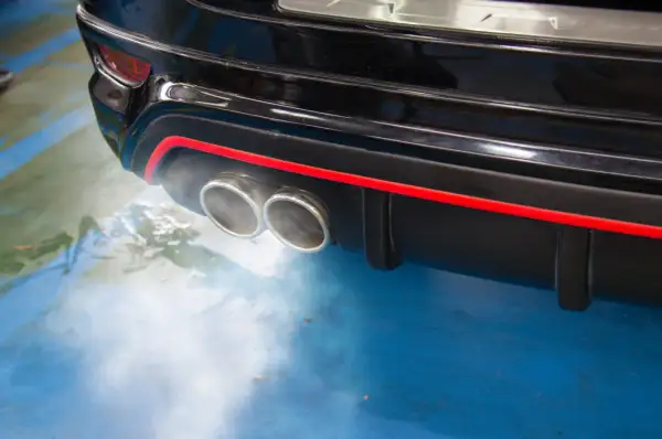 Dym z podwójnej końcówki wydechu czarnego samochodu, sugerujący, dlaczego diesel kopci na czarno.
