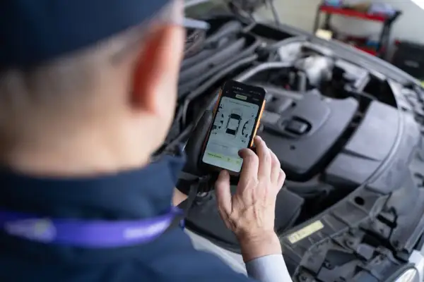Mechanik sprawdza kody błędów DTC Renault na telefonie, analizując raport z pomiarów lakieru i szczelin.