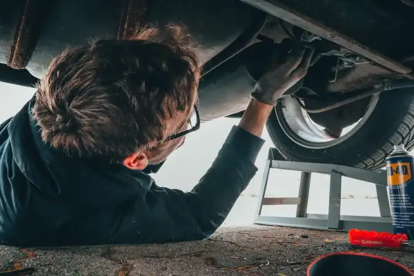 Mechanik bada podwozie auta, szukając przyczyn problemów z elektrozaworem skrzyni biegów. Objawy mogą być różne.