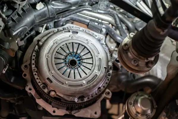 Mechanik pracuje nad grawitacyjnym odpowietrzaniem sprzęgła w samochodzie. Widoczny jest mechanizm sprzęgła i elementy silnika.