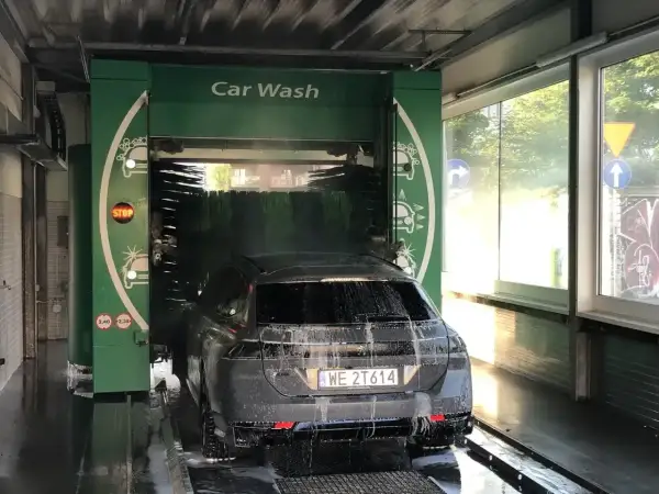 Czarnym autem wjeżdżamy do myjni automatycznej. Piana i szczotki skutecznie usuwają brud, pokazując, czym umyć auto.