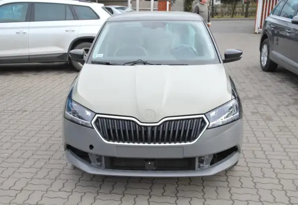 Szara maska samochodu Skoda czeka na malowanie. Widać kratkę grilla i reflektory.