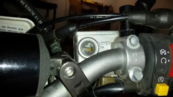 Zbiorniczek płynu hamulcowego motocykla z widocznym poziomem płynu.