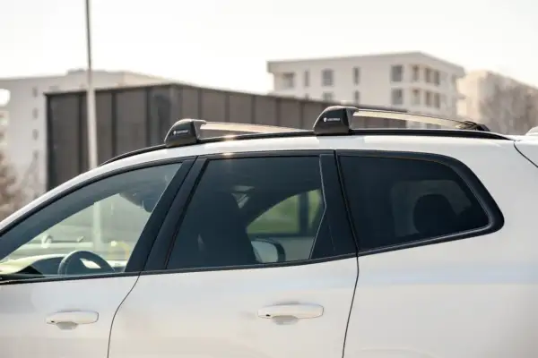 Biały SUV z zamontowanymi relingami dachowymi Yakima. Różne rodzaje relingów dachowych pozwalają na przewożenie bagażu.